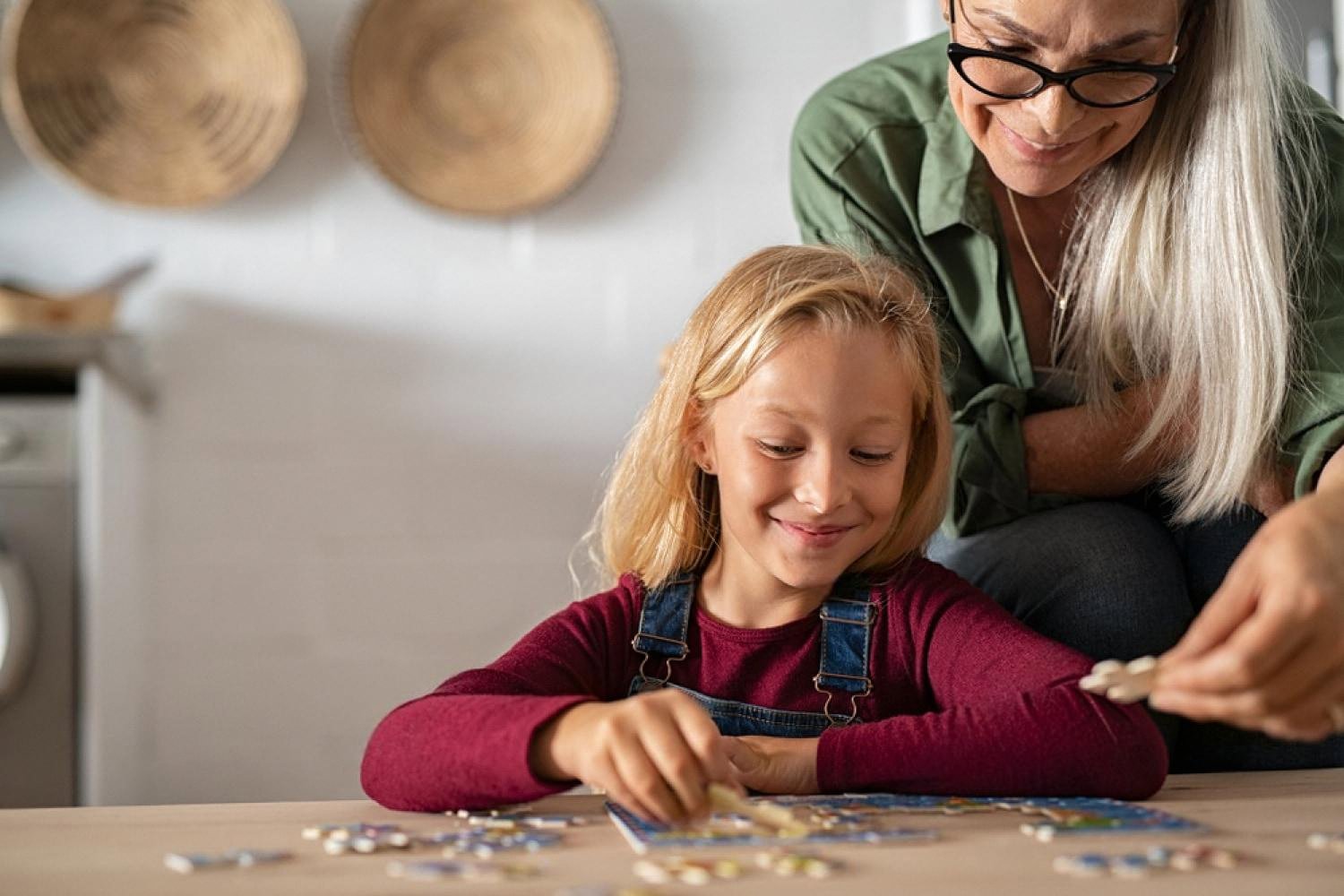 Grandmother and granddaughter solving a jigsaw puzzle together at the kitchen table