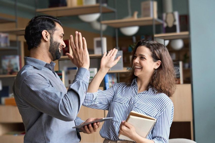Two colleagues in a UAE office giving each other a high five after finishing a task